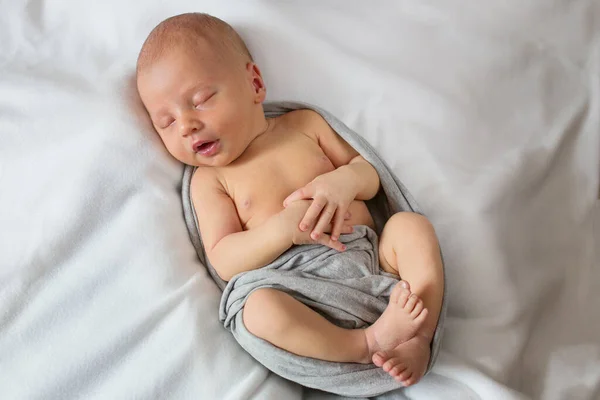 Bebé recién nacido bellamente posando y durmiendo. Niño recién nacido dormido sobre un fondo blanco en una envoltura gris. —  Fotos de Stock