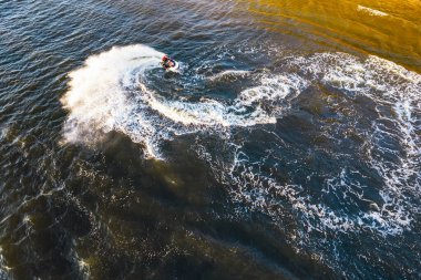 Hava manzaralı, gün batımında skuter süren bir adam. 