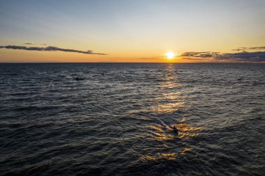Güneşin altın yansıması içinde suyla kayan bir adam