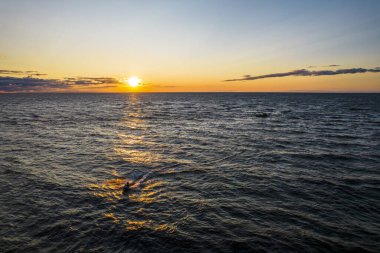 Güneşin altın yansıması içinde suyla kayan bir adam