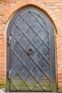 Paslı ve tuğla duvarlı metal kapı.