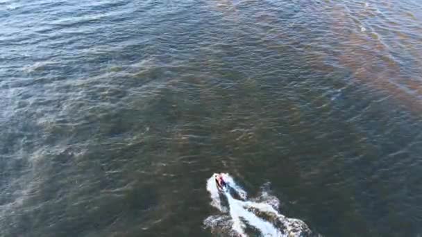 Vista aérea de los paseos del hombre en scooter de agua saltando sobre las olas al atardecer — Vídeo de stock