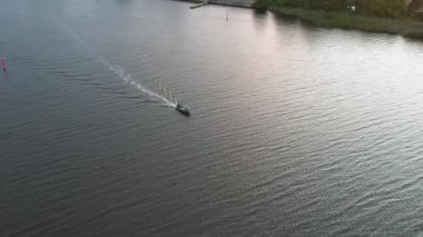 Yeşil bir sahil şeridinin yanındaki beyaz yelkenli teknesinin havadan görünüşü 