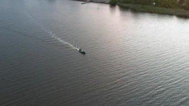 Yeşil bir sahil şeridinin yanındaki beyaz yelkenli teknesinin havadan görünüşü 