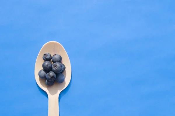 Recycled spoon and juicy, fresh blueberries on color table — Stock Photo, Image