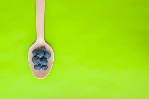 Recycled spoon and juicy, fresh blueberries on green background — Stock Photo, Image