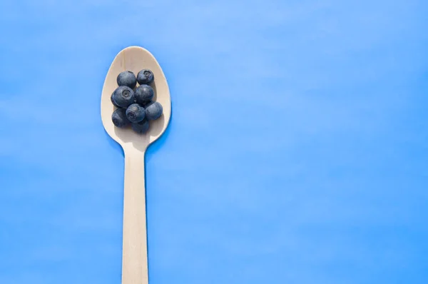 Recycelter Löffel und saftige, frische Blaubeeren auf dem Farbtisch — Stockfoto