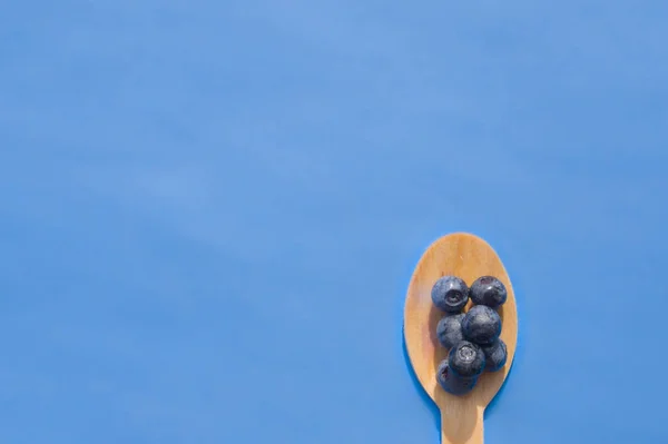 Recycelter Löffel und saftige, frische Blaubeeren auf dem Farbtisch — Stockfoto