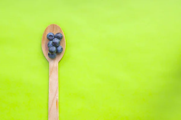 Recycled spoon and juicy, fresh blueberries on green background — Stock Photo, Image