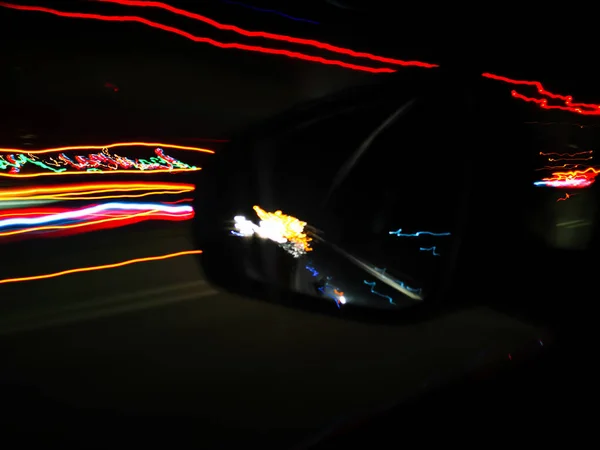 Неоновые полосы и отражение автомобилей в зеркале заднего вида — стоковое фото