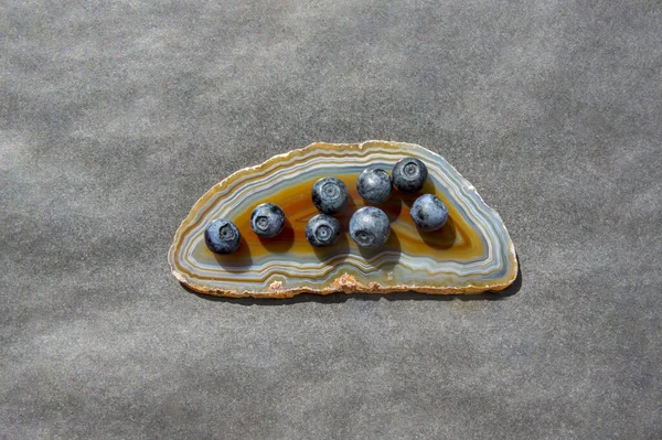 Драгоценный камень агата и сочная черника на черном столе — стоковое фото