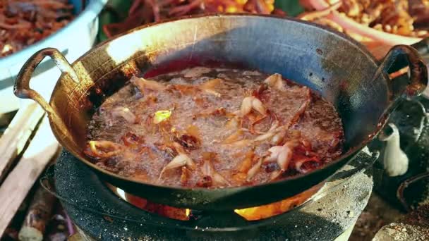 Vrouw met behulp van metalen Tang aan het roer van frituren kikkers in een wok op een huishoudelijke kachel — Stockvideo