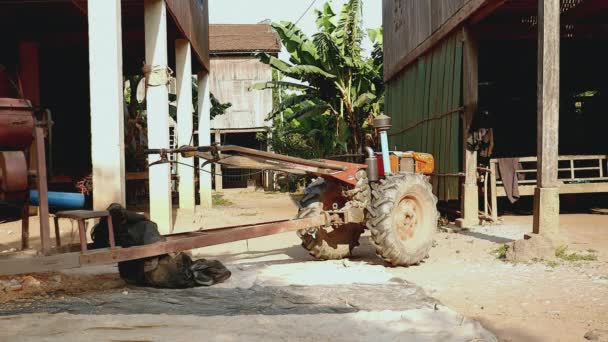 Schwenkschuss auf eine Maisschellmaschine neben Stelzenhäusern in einem landwirtschaftlichen Gebiet — Stockvideo