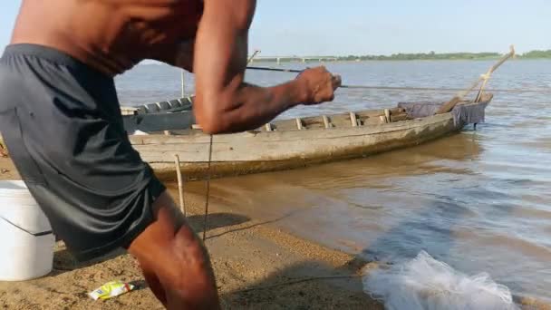 Fisher vytahuje rybářskou síť z řeky na břehu řeky — Stock video