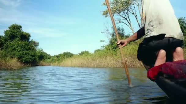 Fisherova veslování z přídě na břehu kánoe na jezeře pod jasnou oblohou — Stock video