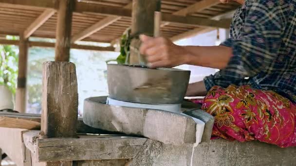 Mujer se sentó con las piernas cruzadas usando piedra de molino vuelta a mano para moler el arroz húmedo para hacer harina de arroz empapada — Vídeos de Stock