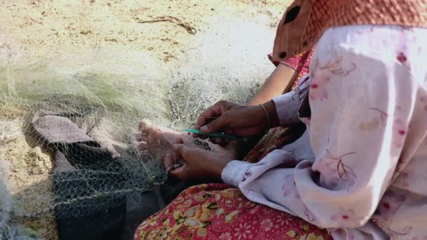 Närbild på en kvinna sitta på flodstranden att laga en fiske netto för hand — Stockvideo