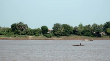 Kampong - Kamboçya - 02-02 - 2015: Küçük motorize kano büyük bir bambu yığınının arkasında nehrin aşağısına çekiliyor.