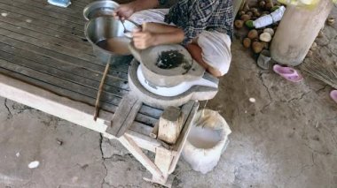 bağdaş kurup sırılsıklam pirinç unu yapmak için ıslak pirinç öğütmek için el döndü millstone kullanarak kadın oturdu