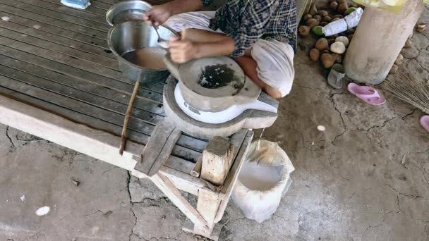 Femme assise jambes croisées à l'aide de meule tournée à la main pour moudre du riz humide pour faire de la farine de riz trempée — Video