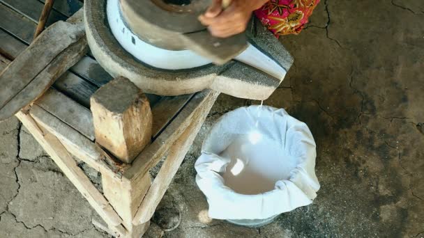 Mujer se sentó con las piernas cruzadas usando piedra de molino vuelta a mano para moler el arroz húmedo para hacer harina de arroz empapada — Vídeos de Stock