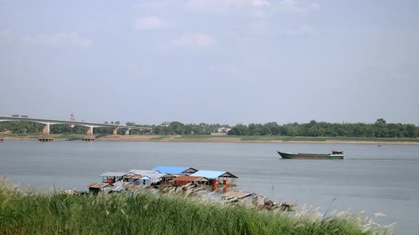 Vista del río a una barcaza que baja río abajo cerca de un puente. Casas flotantes en primer plano — Vídeos de Stock