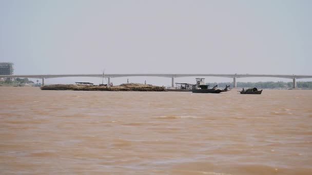 Barge tirant derrière un grand tas de poteaux de bambou vers la rive — Video