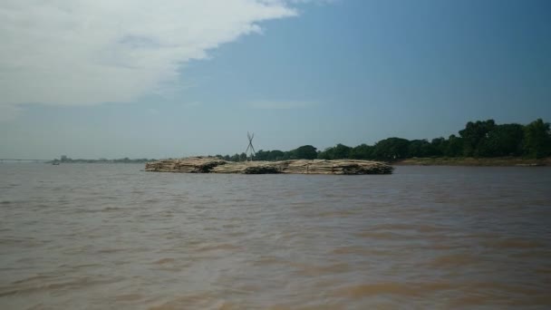 zadní pohled na člun se táhne za velkou hromadou bambusových tyčí po řece