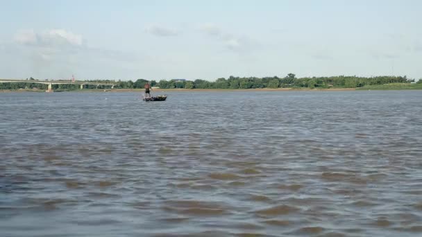 Pêcheur ramant son petit bateau sur la rivière tout en tirant un filet de pêche à travers l'eau derrière — Video