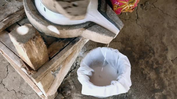 Mujer se sentó con las piernas cruzadas usando piedra de molino vuelta a mano para moler el arroz húmedo para hacer harina de arroz empapada — Vídeos de Stock