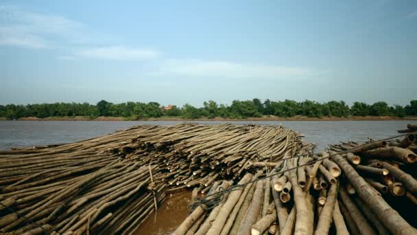 Montones de postes de bambú remolcados por un pequeño barco río abajo — Vídeos de Stock