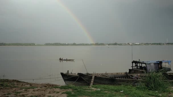 Rainbow over rivier en kleine vissersboot passerende binnenvaartschepen baggeren vastgebonden op rivieroever — Stockvideo