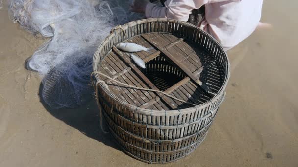 Pêcheur enlever les prises de poissons enchevêtrés et le garder dans un panier en bambou — Video