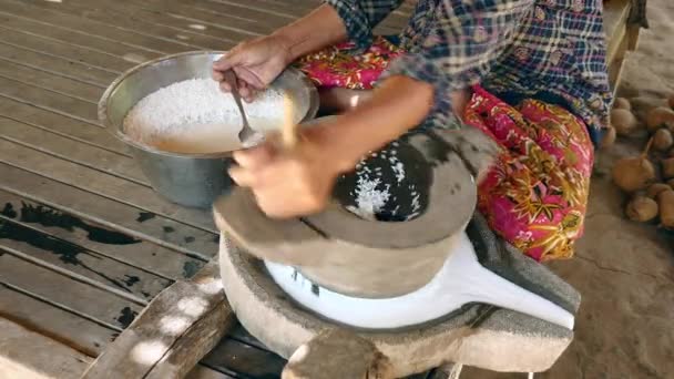 Mujer se sentó con las piernas cruzadas usando piedra de molino vuelta a mano para moler el arroz húmedo para hacer harina de arroz empapada — Vídeos de Stock