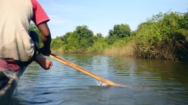 Fisher remando do lado da proa uma canoa escavada em um lago sob céu limpo — Vídeo de Stock