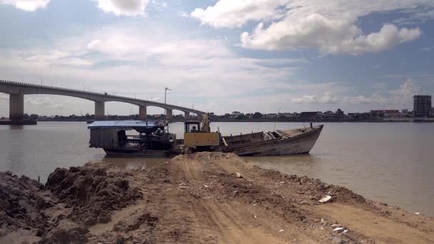 Excavadora esperando para mover la arena del río dragado de una barcaza de bombeo de arena — Vídeos de Stock