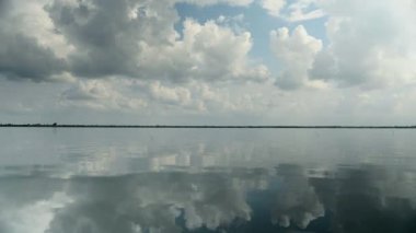 Göl suya yansıyan mavi gökyüzünde beyaz ve gri bulutlar