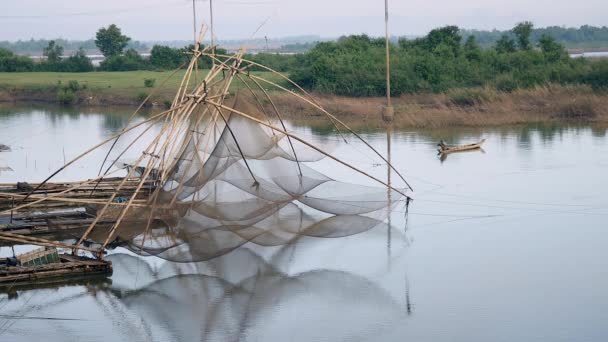 Отражение китайских рыболовных сетей в озере и рыбака в каноэ на заднем плане — стоковое видео