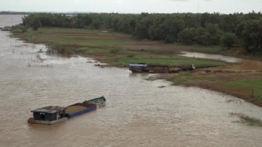 Küçük bir kamyon üzerine bir mavna üzerine dredged nehir kum boşaltma bir ekskavatör Riverside geniş açı görünümü