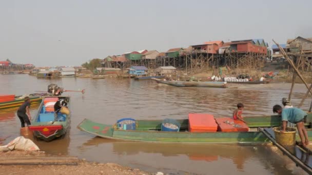 漁船で釣った魚を川の端に閉じ込めます 背景に浮かぶ村 — ストック動画