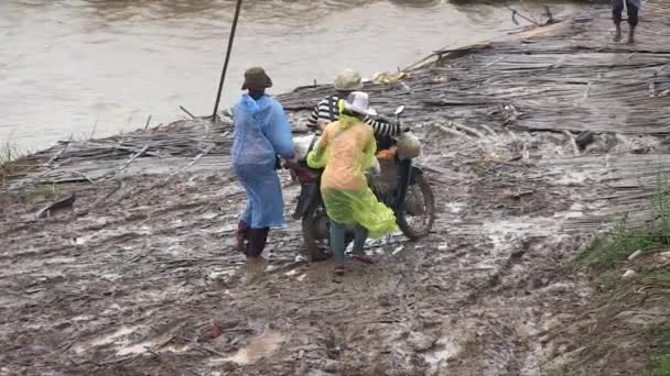 Frauen Schieben Ein Motorrad Auf Einem Schlammigen Uferweg Regen Auf — Stockvideo