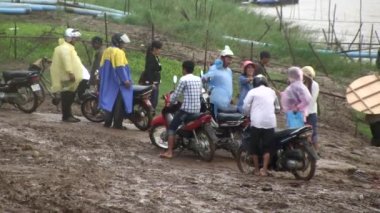 İskeleden kasabaya giden çamurlu bir yolda yürüyen feribot yolcuları.