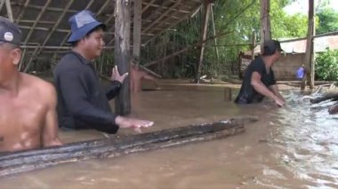 Su basmış bir depodaki bambu direklerini boşaltan işçilere yakın durun.