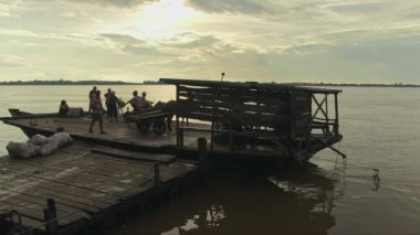 Gün doğumunda birkaç yolcu taşıyan feribot rıhtımdan ayrılıyor.