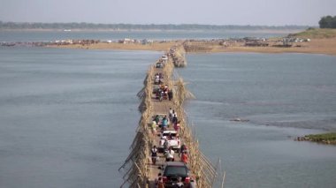 Mekong Nehri üzerindeki bambu köprüsündeki trafik sıkışıklığının üst görüntüsü; motosikletler, arabalar ve bisikletlerin geçişi.