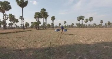  Omzunda palmiye özü dolu plastik kaplar taşıyan bir musluğun arkasına uç. 