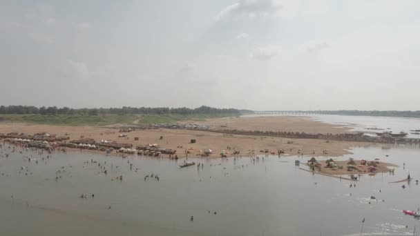 人々の群衆の空中スライダーショットは 砂のビーチに広がる木製のバンガローで 泳ぐために集まっている 竹橋の渋滞を背景に — ストック動画