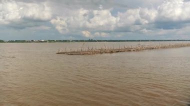 Mekong nehrinde yüzen kırık bambu köprüsünün yanından geçen eski bir mavna. 