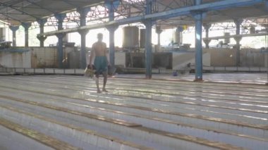  worker is pouring water diluted with acid which allows the latex to coagulate