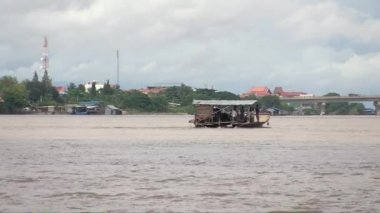Yolcularla nehri geçen bir feribotun arka görüntüsü. Arkaplanda köprü